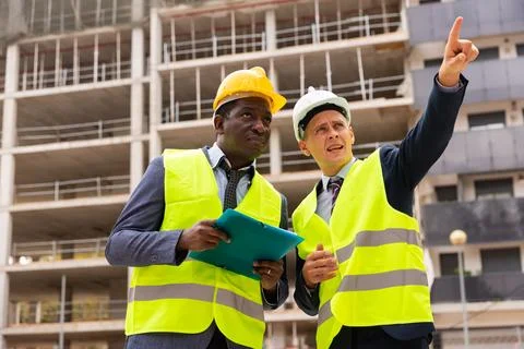 Foreman showing builder something at the construction site by pointing hand Stock Photos