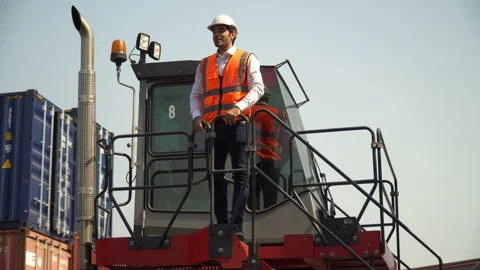 Foreman standing on cabin forklift while moving talking to worker control loa Stock Footage 156383385