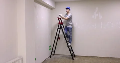 Foreman stands on ladder checking state of plastered wall Stock Footage 238517745