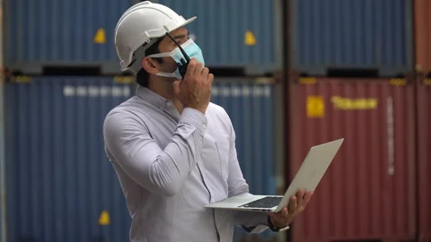 Foreman wareing face mask holding laptop computer talking on the walkie-talki Stock Footage 139095192
