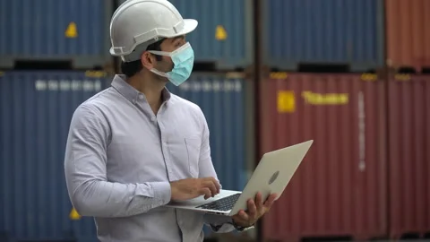 Foreman wareing face mask holding laptop computer checking  Containers box at Stock Footage 139095198