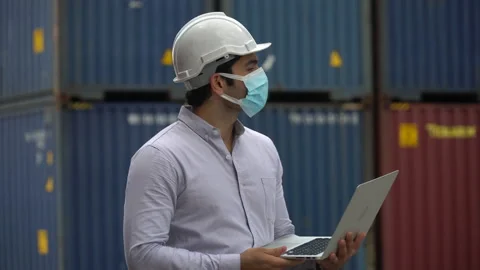 Foreman wareing face mask holding laptop computer talking on the walkie-talki Stock Footage 139095332