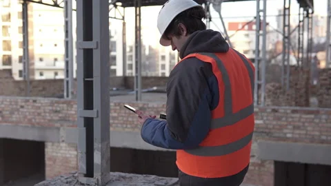 A foreman in a white helmet with a smartphone at a construction site works. Stock-Footage 147644287