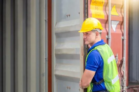 Foreman worker in hard hat and safety vest checking containers box from cargo Фото