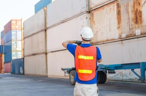 Foreman worker in hard hat talks on two-way radio control loading containers box Stockfoto's