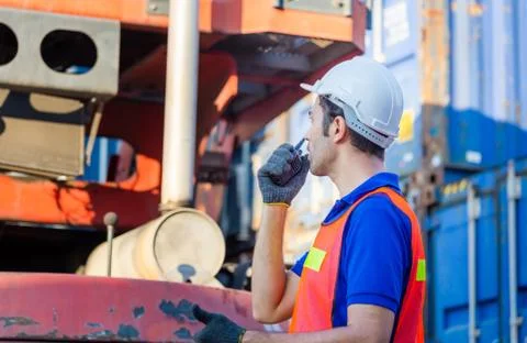 Foreman worker in hard hat talks on two-way radio control loading containers box Photos