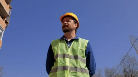Foreman in a yellow helmet with a beard  goes near the house under construction Stock Footage 106020020