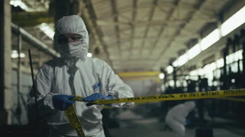 Forensic expert in protective uniform securing crime scene with police tape Video stock 335458454