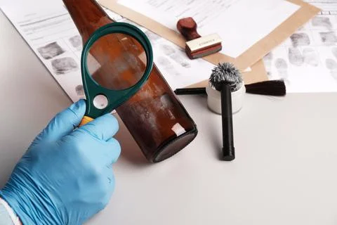 Forensic expert using a magnifying glass examines fingerprints on evidence -  Foto stock