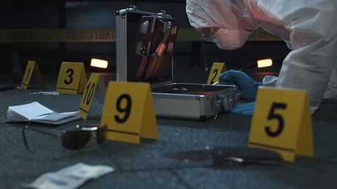 Forensic expert working at crime scene of drug dealer murder. Many evidence tags Stock Photos