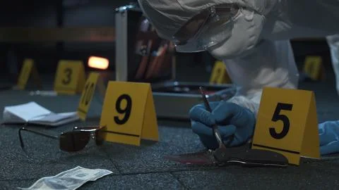 Forensic expert working at crime scene of drug dealer murder. Many evidence tags Stock Photos