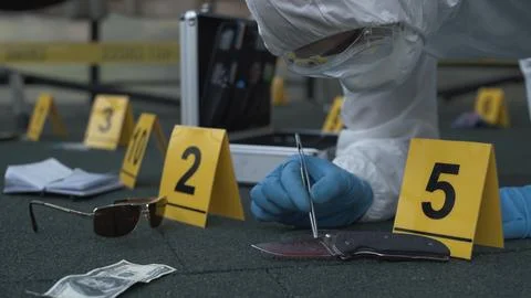 Forensic expert working at crime scene of drug dealer murder. Many evidence tags Stock Photos