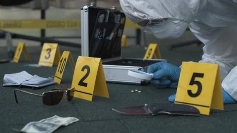Forensic expert working at crime scene of drug dealer murder. Many evidence tags Stock Photos