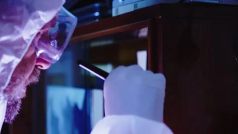 Forensic guy collects DNA sample from crime scene in ultra violet light Stock Footage 313274865