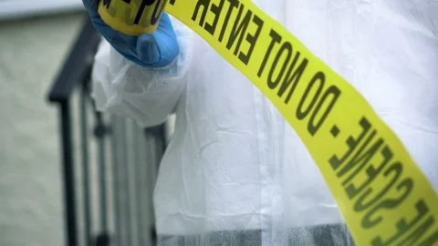 Forensic officer pulling barricade tape from roll Stock Footage 110746551