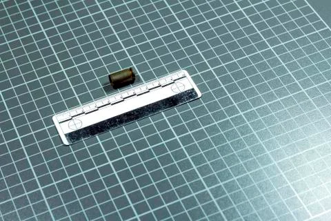 The forensic ruler rests on a laboratory checkered background next to the shot Stock Photos