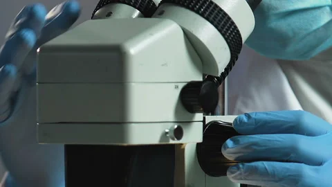 Forensic scientist carefully examines physical evidence under microscope closeup Stock Footage 87151064