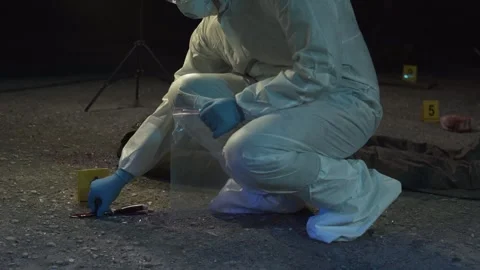 Forensic scientist picking up knife, placing it in evidence bag at crime scene.  Video stock 283865771