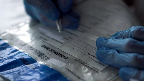 Forensic scientist writing on evidence bag at crime scene Video stock 110714335