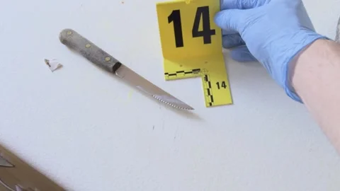 Forensic specialist placing an evidence marker next to a knife Video stock 330574270