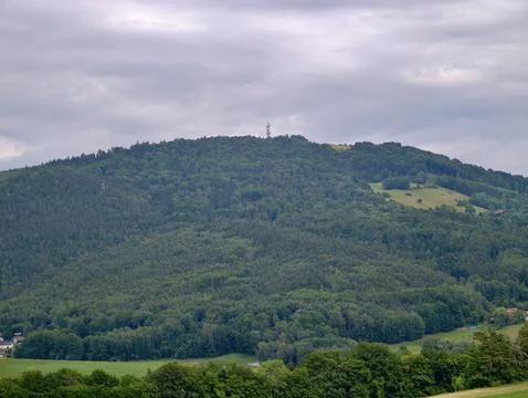 Forest covered hillside with communications tower beneath heavy overcast sk.. Fotos Stock