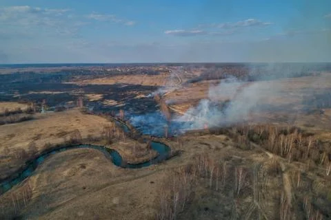 Forest fire. Dry grass burning in the field, near the river. Stock Photos