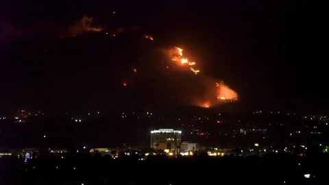 Forest fire on mountain range above residential neighborhood at night as Vídeos de archivo 120055624