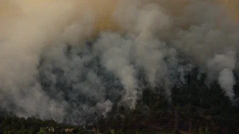 Forest fire on side of a mountain ridge close to houses, Stockbeeldmateriaal 92605912