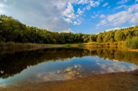 Forest lake with clouds reflected in the water Stock Photos