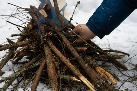 In the forest, a man makes a fire by setting dry firewood on fire to keep warm Stock Photos