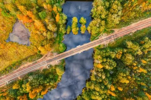 Forest river with sky reflection crossed by railroad Foto stock