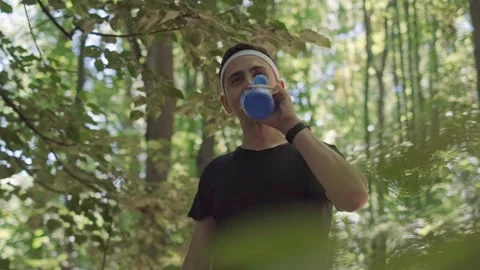 Forest running to boost productivity. A man stands in the park with a sports wat Stock Footage 280186362
