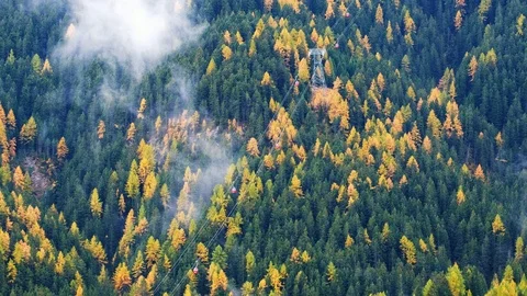 Forest trees with clouds and mist fog  and red ski lift in Dolomites Stock Footage 86289701