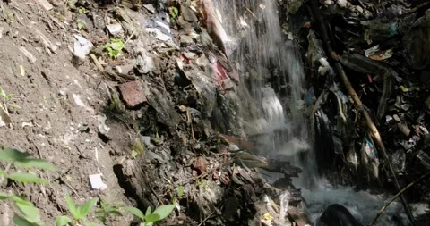 Forest waterfall stream among garbage in nature, ecology disaster in wild place. Stock Footage 135028482