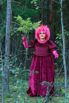 The forest witch in purple clothes performs an magical ritual with a fern. Stock Photos