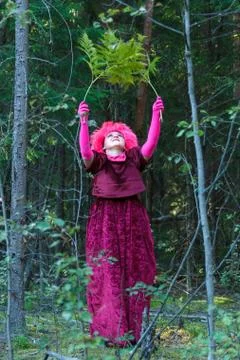 The forest witch in purple clothes performs an magical ritual with a fern. Stock Photos