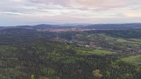 Forested hills above patchwork fields and valley town at dusk with rolling Stock Footage 342355425