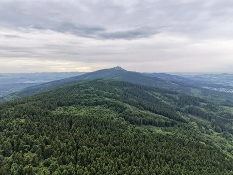 Forested hills with distant tower under cloudy sky Stock-Fotos
