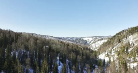 Forested mountain slopes descend gently toward saddle Видео 318743286