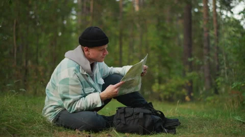 Forester analyzes trail map carefully, Adventurer studies detailed forest route Stock Footage 333655936