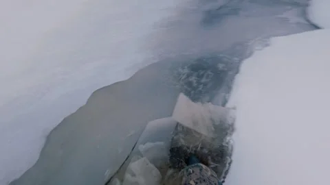 The forester walks on the thin ice of the river and breaks it with his feet. Video stock 322092505