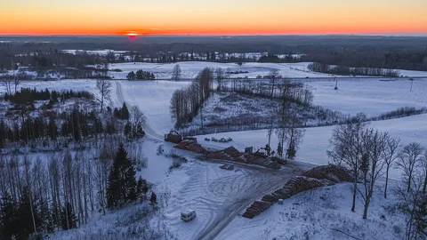 A Forestry Crane Loads Timber Logs in a Snowy Field - Aerial Hyperlapse Video stock 333325070
