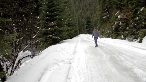 Forestry worker who goes on a road with snow through the forest and then down Stock Footage 78218318