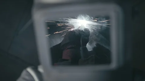 Forge workshop. Smithy. Worker in a welding hood helmet welds a part by electric Stock Footage 121000882