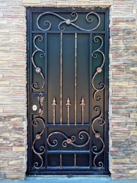 Forged gilded pattern on a black gate. Black gate with forged pattern Stock Photos