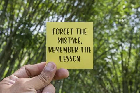 Forget the mistake, remember the lesson written on yellow adhesive note with Stock Photos