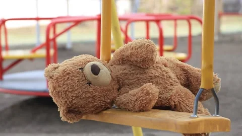 Forgotten Bear on a Childrens Swing in an Empty Playground Stock Footage 154046217