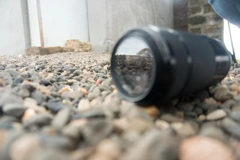 Forgotten Camera Lens Lying on Pebble-Strewn Terrain - Photography Equipment. Foto stock