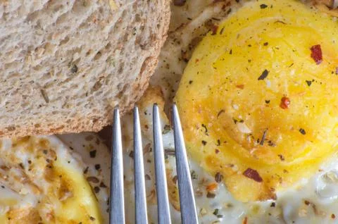 A fork aiming at fried eggs and toast with seasoning. Healthy breakfast. Foto stock