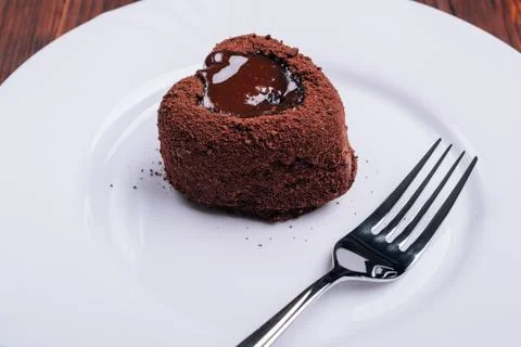Fork and chocolate cake in the shape of a heart on a white plate Stock Photos